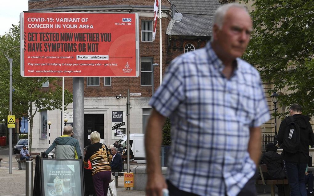 Een wandelaar passeert een waarschuwingsbord in Blackburn, Noordwest-Engeland. De Britse overheid stelt verder versoepelen van de coronaregels vier weken uit vanwege de zorgelijke deltavariant uit India. beeld AFP, Oli Scarf