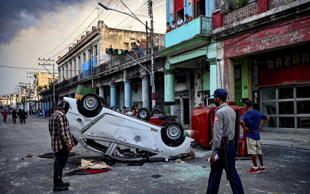 Een politieauto is vernield tijdens protesten in de Cubaanse hoofdstad Havana. beeld AFP, Yamil Lage