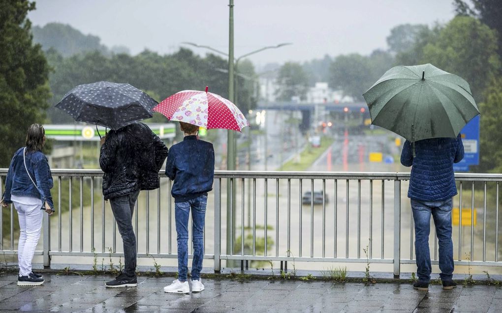 Een auto is in het water achtergelaten op de A79 bij Heerlen. Hevige regenval zorgde dinsdag in Limburg en delen van België en Duitsland voor veel problemen. beeld ANP, Marcel van Hoorn