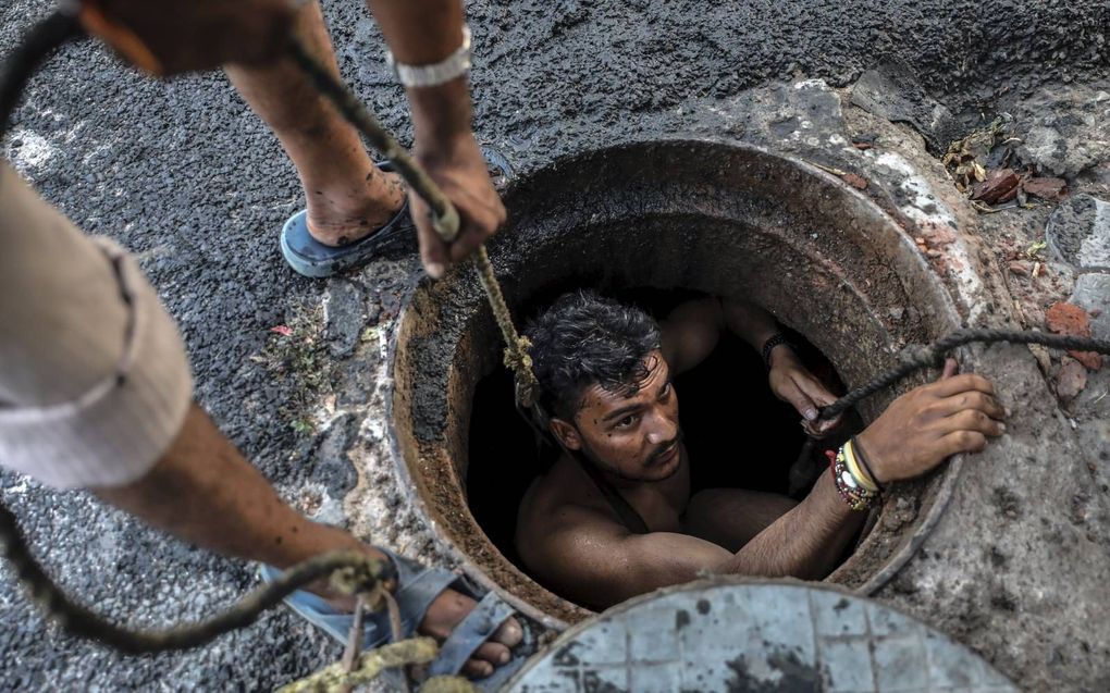 Een dalit maakt een riool schoon, zonder veiligheidsmaatregelen. beeld EPA, Rajat Gupta