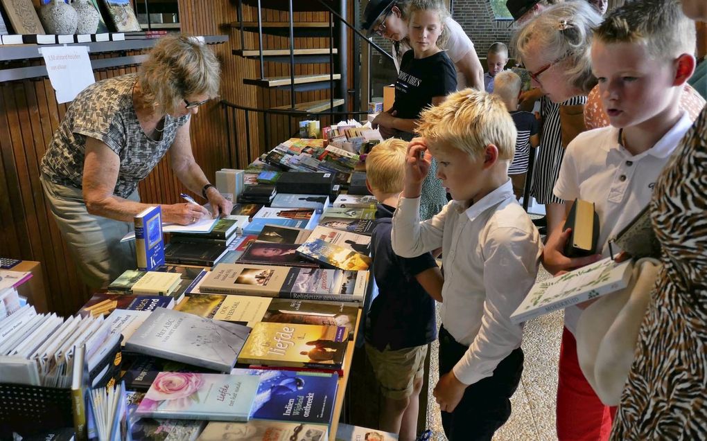 Drukte bij de boekentafel op de zendingsmiddag voor het Noorden in de christelijke gereformeerde kerk in Damwoude. beeld Jan van Reenen