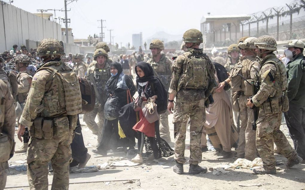 Britse en Amerikaanse militiaren begeleiden op de luchthaven van Kabul de evacuatie uit Afghanistan.  beeld AFP