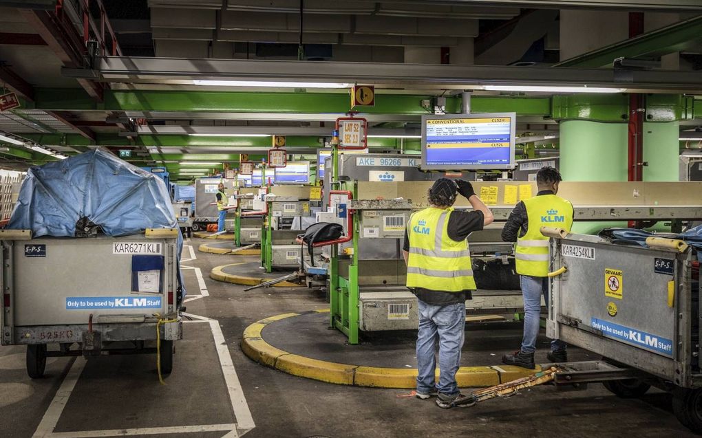 Bagagemedewerkers slepen met koffers en tassen in de kelders van de luchthaven Schiphol. beeld RD, Henk Visscher