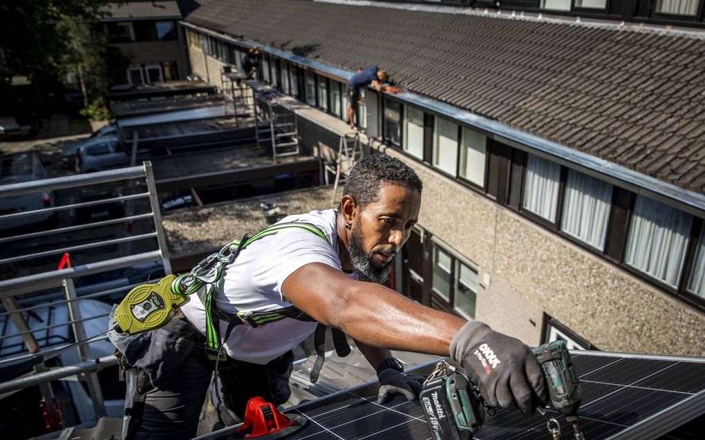 Een installateur plaatst zonnepanelen op het dak van een woonhuis in Gouda. Zo’n 1,5 miljoen huizen in Nederland maken inmiddels gebruik van zonnepanelen.  beeld ANP, Remko de Waal