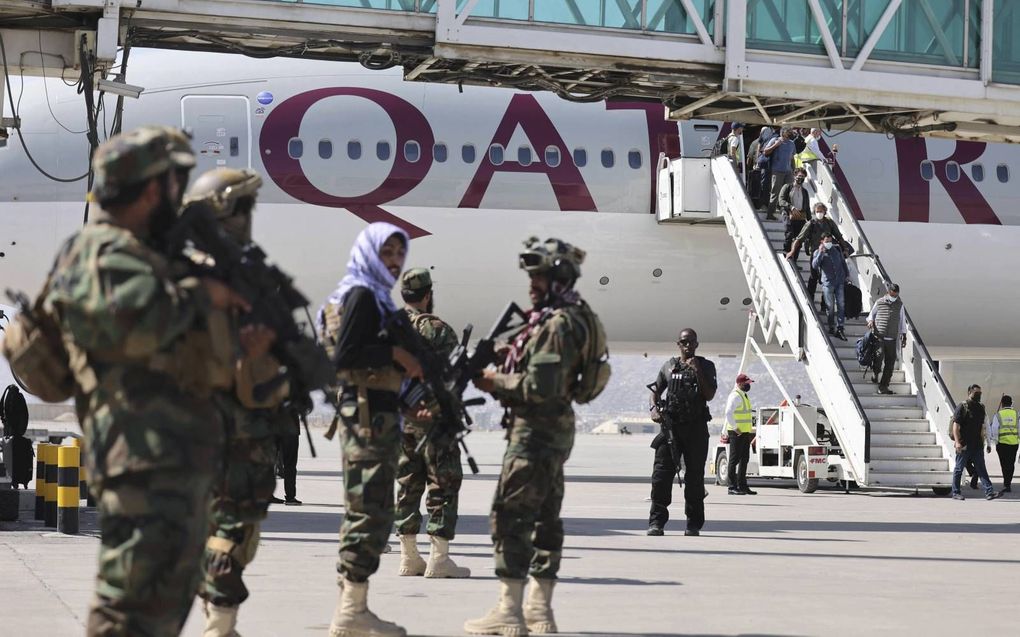 Talibanstrijders kijken toe als passagiers dinsdag een toestel van Qatar Airways verlaten op de luchthaven van de Afghaanse hoofdstad Kabul. beeld AFP, Karim Sahib