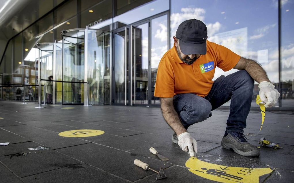 Een medewerker van het Stedelijk Museum in Amsterdam verwijdert stickers waarop bezoekers op de afstandsregel worden gewezen. beeld ANP, Koen van Weel