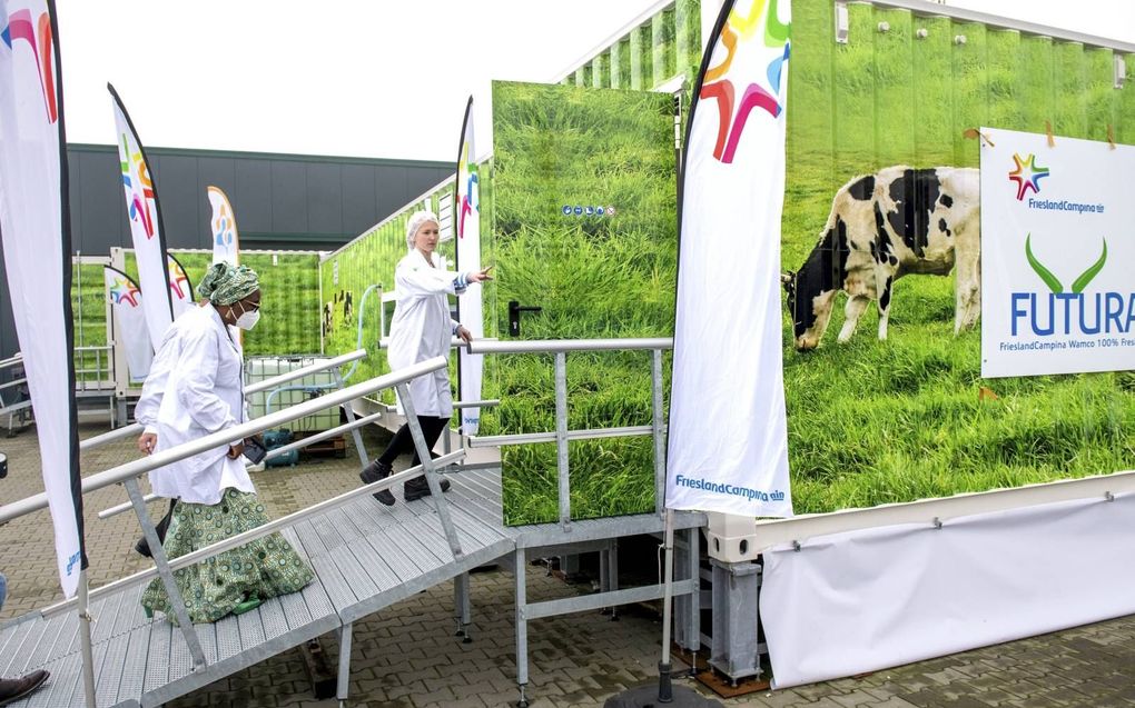 Een medewerker van FrieslandCampina opent de deur van de mobiele yoghurtfabriek voor de Nigeriaanse ambassadeur Eniola Olaitan Ajayi, de dame in de groene jurk. beeld Jilmer Postma