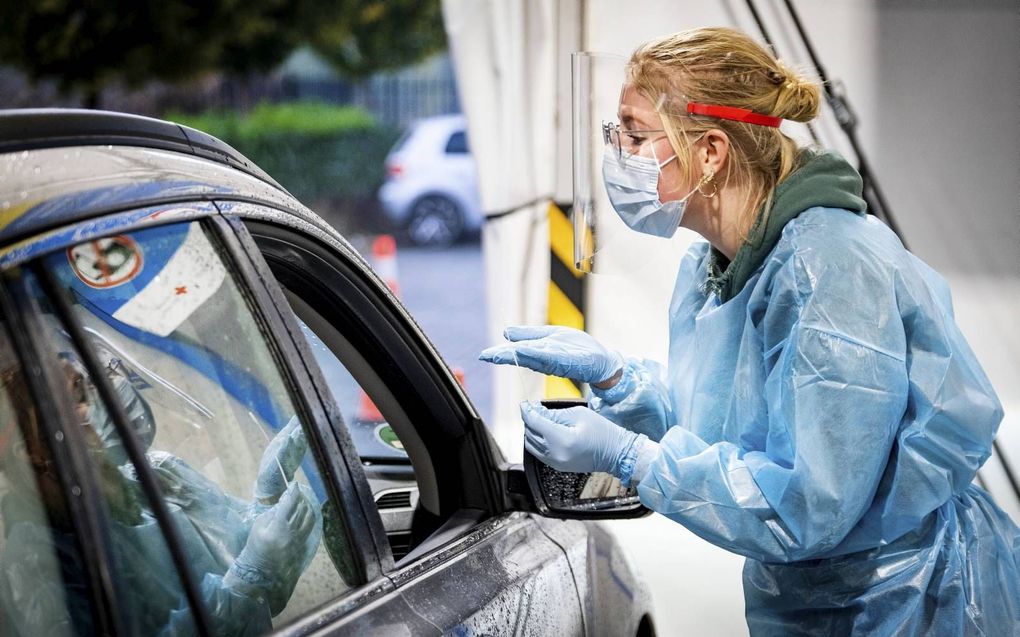 Een GGD-medewerker voert een coronatest uit in een teststraat. Beeld ANP, Ramon van Flymen