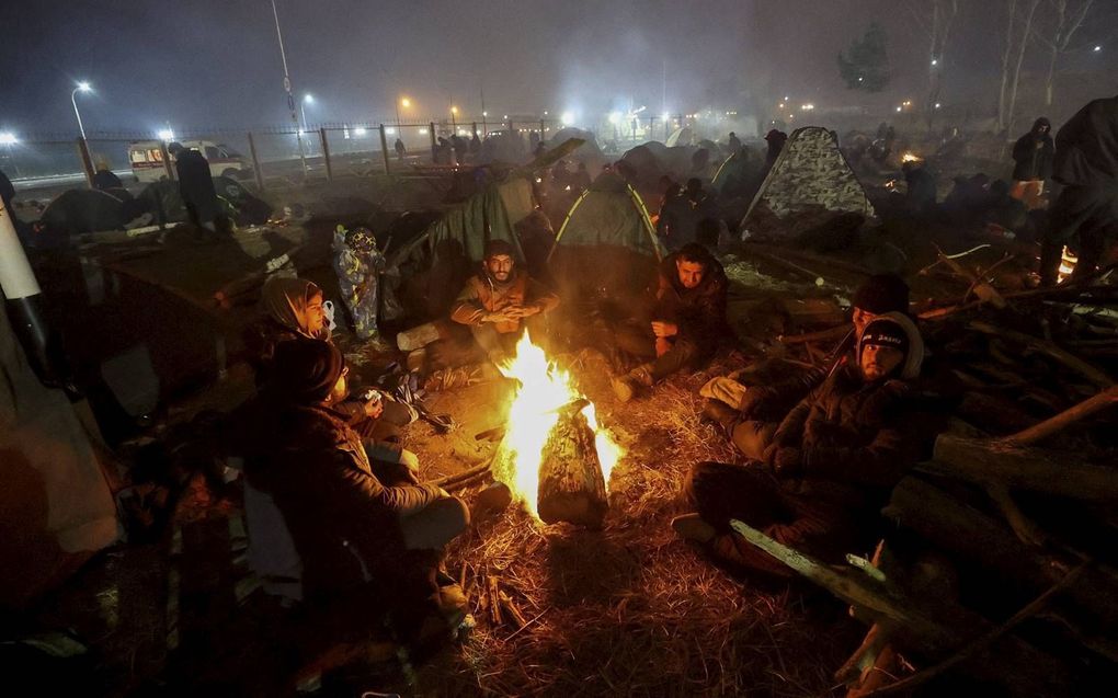 Migranten aan de grens met Polen verwarmen zich rond een houtvuur. beeld AFP