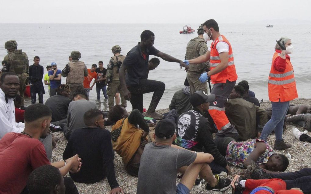 Migranten worden bij aankomst in Ceuta opgevangen door Spaanse militairen en medewerkers van het Rode Kruis. In mei probeerden duizenden migranten vanuit Marokko via de Middellandse zee de Spaanse enclave te bereiken. beeld EPA, Reduan