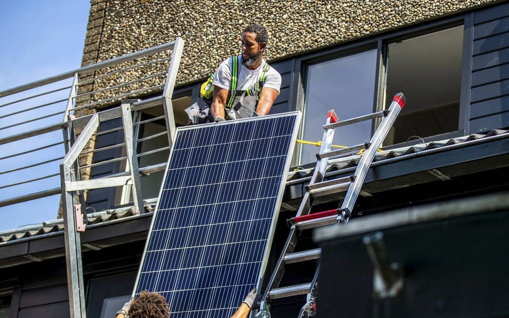 Twee installateurs plaatsen zonnepanelen op het dak van een woonhuis. beeld ANP, Remko de Waal