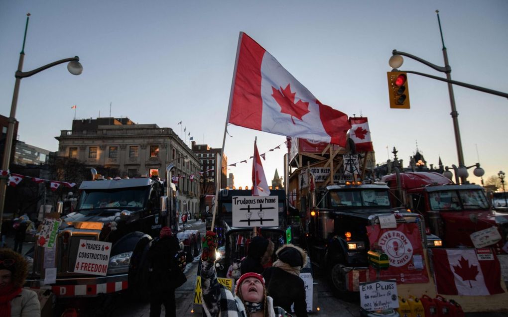 Een demonstrant houdt de Canadese nationale vlag vast tijdens een protest dinsdag van vrachtwagenchauffeurs buiten het parlement van Canada in Ottawa. beeld AFP, Ed Jones