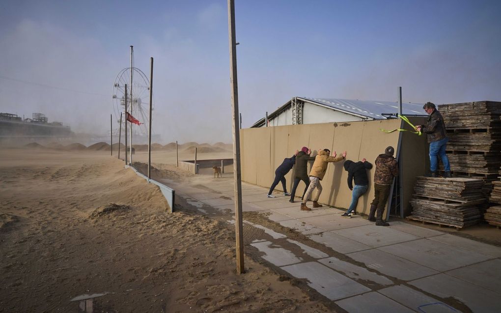 Met man en macht probeert een strandtenthouder te voorkomen dat zijn tent wegwaait. beeld ANP