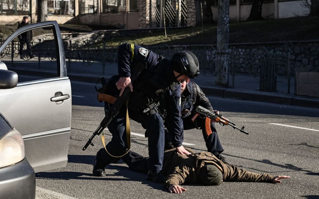 Oekraïense politieagenten pakken een verdachte persoon op bij een checkpoint in Kiev. beeld AFP, Aris Messinis