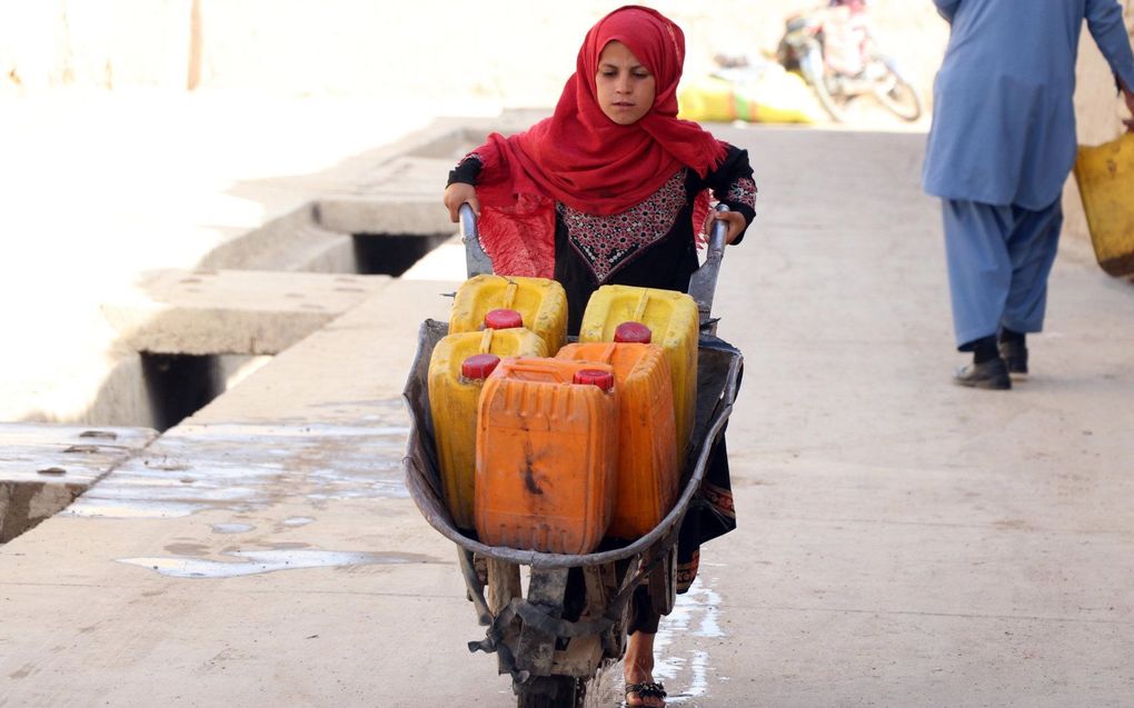 Een Afghaans meisje draagt water, in de provincie Kandahar. beeld EPA