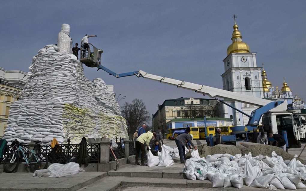 Met zandzakken proberen donderdag vrijwilligers in Kiev monumenten te beschermen. Ze nemen de aangekondigde Russische terugtrekking met een korreltje zout. beeld AFP, Genya Savilov