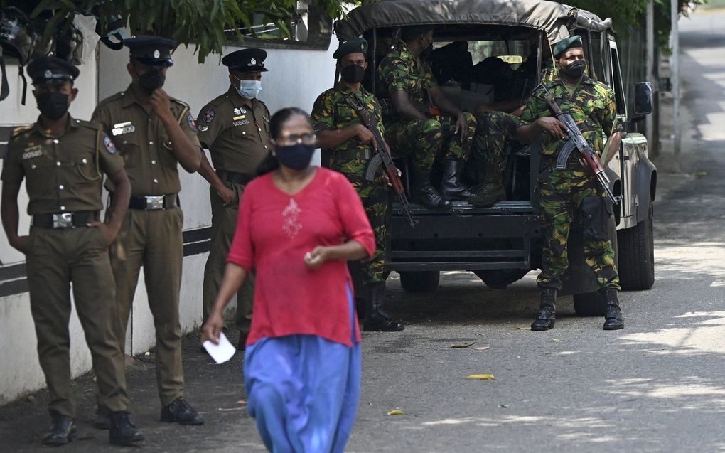 Een voetganger loopt langs de Special Task Force (STF) en politiepersoneel dat op wacht staat langs een straat in Colombo. In Sri Lanka werden troepen met verregaande bevoegdheden ingezet om verdachten vast te houden nadat de president de noodtoestand had uitgeroepen omdat de protesten tegen hem escaleerden. beeld AFP, 
Ishara S. Kodikara