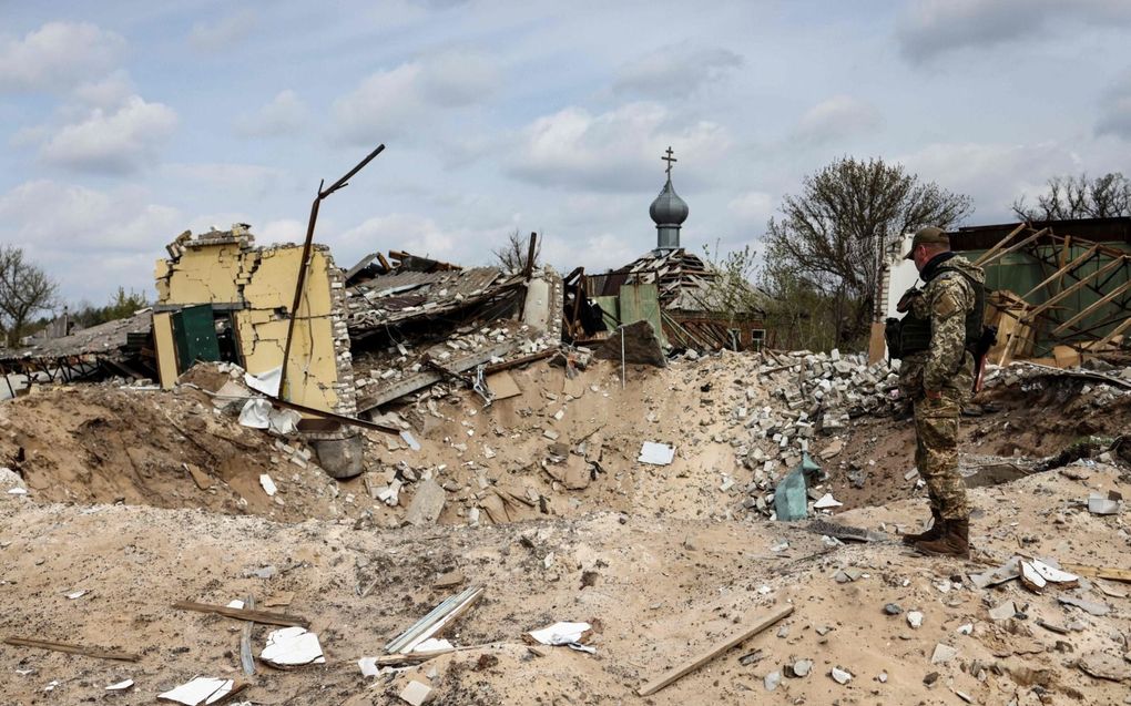 Een Oekraïense militair kijkt naar een bomkrater en vernielde huizen in het dorpje Jatskivka in het oosten van Oekraïne. Rusland heeft maandag de aanval ingezet op dit gebied. beeld AFP, Ronaldo Schemidt