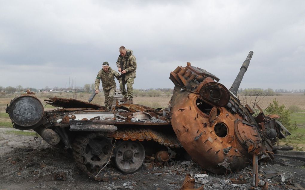 Ukraïense militairen inspecteren een uitgeschakelde Russische tank in Rusaniv, in de buurt van Kiev. beeld EPA, Sergey Dolzhenko