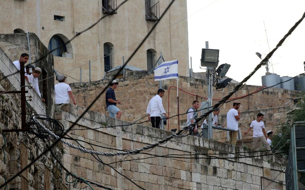 Joods-Israëlische kolonisten kijken naar Palestijnse demonstranten in het Kasbah-gebied van de oude stad Hebron op de Westelijke Jordaanoever. beeld EPA, Abed Al Hashlamoun