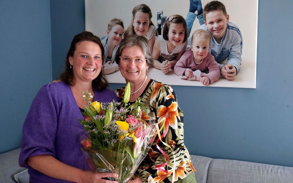 Elly Lugtenburg-Nagtegaal (r.) geeft een bloemetje aan haar dochter Annemieke IJmker-Lugtenburg omdat die zich elke dag inzet om voor haar drukke gezin te zorgen. beeld Cor de Kock