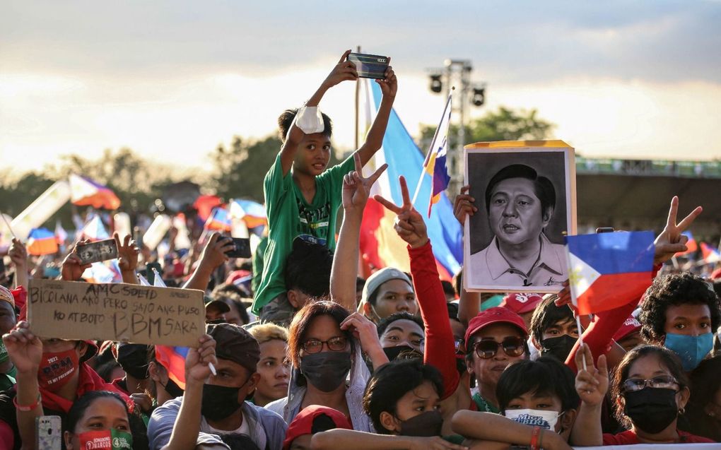 Aanhangers van presidentskandidaat Ferdinand ‘Bongbong’ Marcos junior wonen een campagnebijeenkomst bij in een voorstad van Manilla. De Rooms-Katholieke Kerk heeft zich indirect negatief over hem uitgelaten omdat Marcos in zijn campagne de geschiedenis, waarin zijn vader een dubieuze rol speelde, probeert te verdraaien. beeld AFP, Jam Sta Rosa