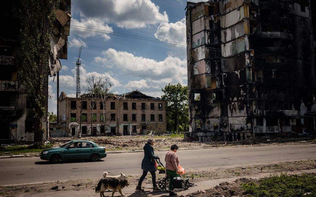 Inwoners van de Oekraïense stad Borodyanka lopen tussen door Russische artilleriebeschietingen zwaarbeschadigde gebouwen. In de ten westen van Kiev gelegen stad zwijgen op dit moment de wapens en wordt voor zover mogelijk gewerkt aan het opknappen van wat is beschadigd.  beeld AFP, Dimitar Dilkoff