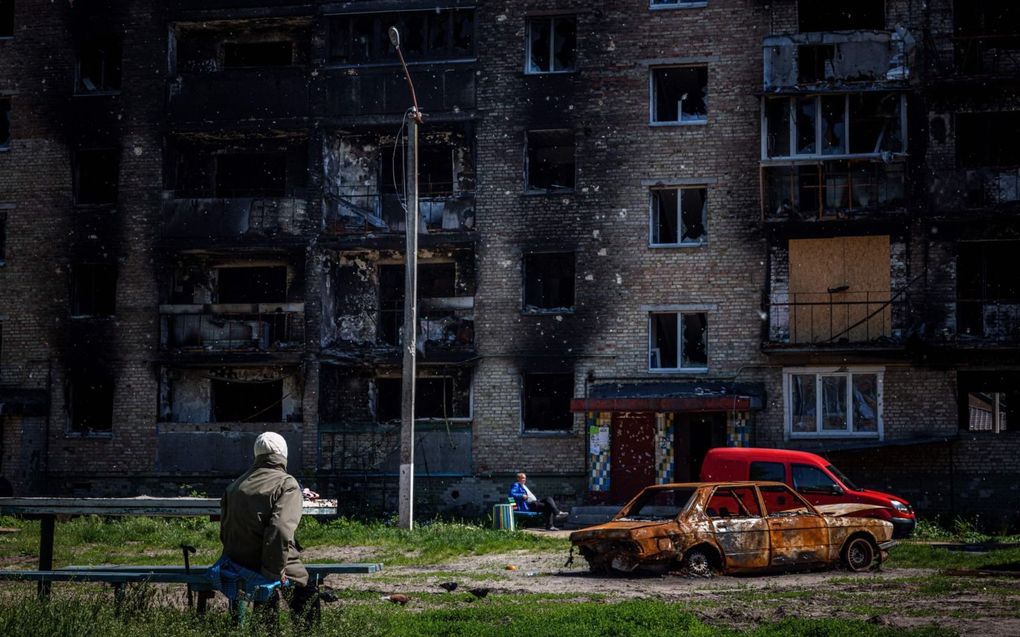 Burgers zitten gelaten voor een kapotgeschoten wooncomplex in Irpin. De oorlog in Oekraïne duurt nu honderd dagen. beeld AFP, Dimitar Dilkoff