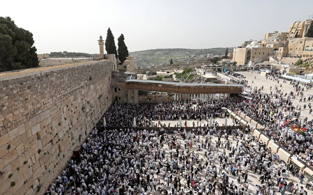 Een mensenmenigte bij de Kotel, de Westelijke (Klaag)muur in Jeruzalem, aan de westzijde van de plek waar de Tweede Tempel zich bevond. De foto is genomen tijdens Pesach, in april. Vele duizenden orthodoxe Joden, gehuld in gebedskleden, ontvingen de priesterlijke zegen („De Heere zegene u en behoede u...”; Num. 6), uitgesproken door de kohanim, mannen die stammen uit priesterlijke families. beeld EPA, Abir Sultan