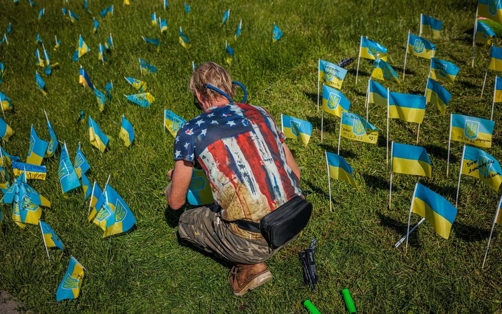 Een man plant Oekraïense vlaggen met daarop de namen van mensen die zijn gedood tijdens de Russische invasie op het Onafhankelijkheidsplein in Kiev. beeld AFP, Dimitar Dilkoff