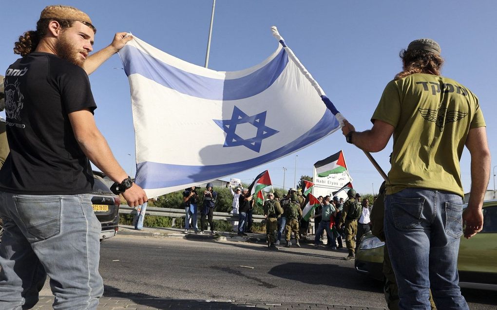 Demonstranten met de Israëlische vlag (op de voorgrond) en met de Palestijnse vlag. beeld AFP, Jaafar Ashtiyeh