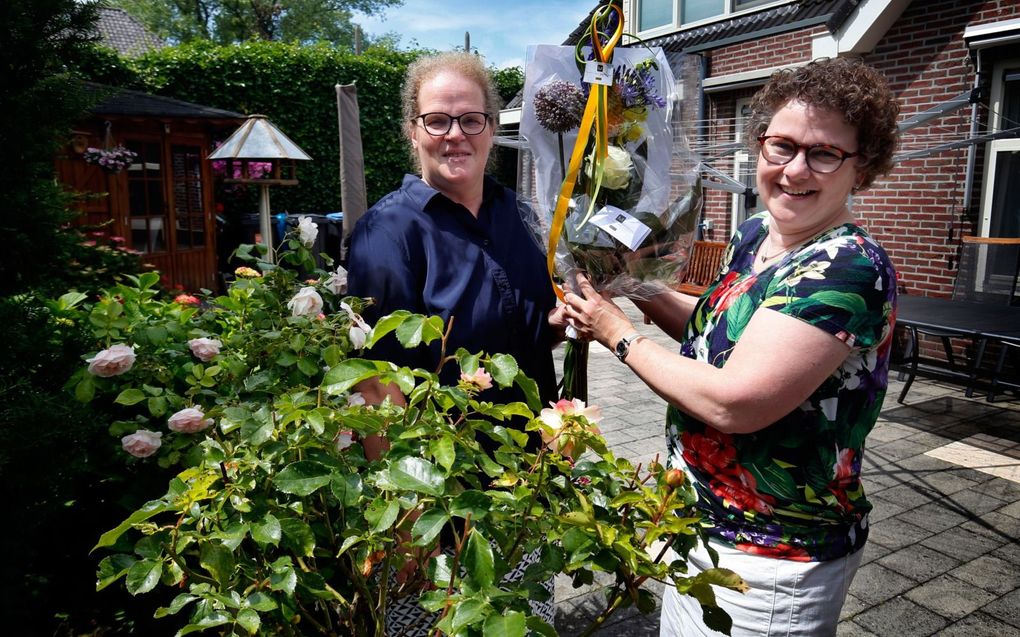 Coby de Jong-Oomen (l) geeft oud-klasgenoot en goede vriendin Ina van Oversteeg bloemen. ”Als oud-klasgenoten zien we elkaar jaarlijks.” beeld Cor de Kock