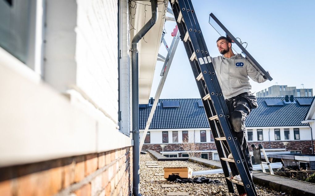 Twee monteurs installeren zonnepanelen op het dak van een woning. Veel consumenten kiezen voor zonnepanelen om zo de maandelijkse energiekosten te drukken. beeld ANP, Jeffrey Groeneweg