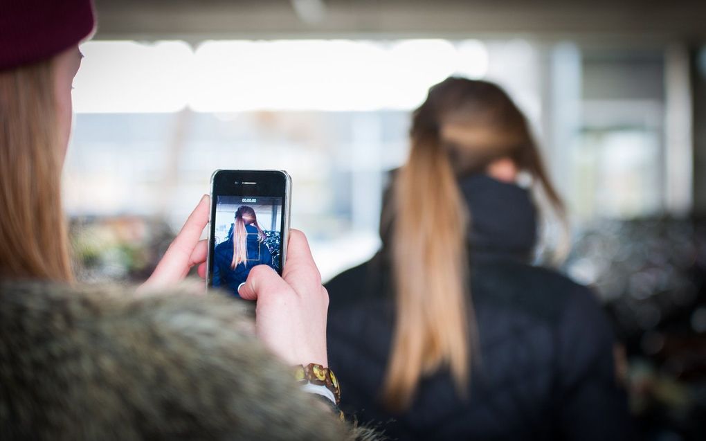 Een scholiere pest een schoolgenootje, en filmt dit met een smartphone. beeld ANP, ROOS KOOLE