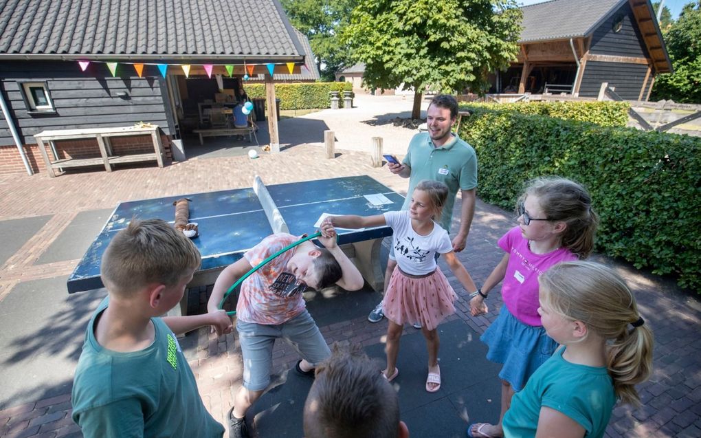 De kinderen doen in de schaduw een hoepelspel onder leiding van een van de meesters. beeld Herman Stöver