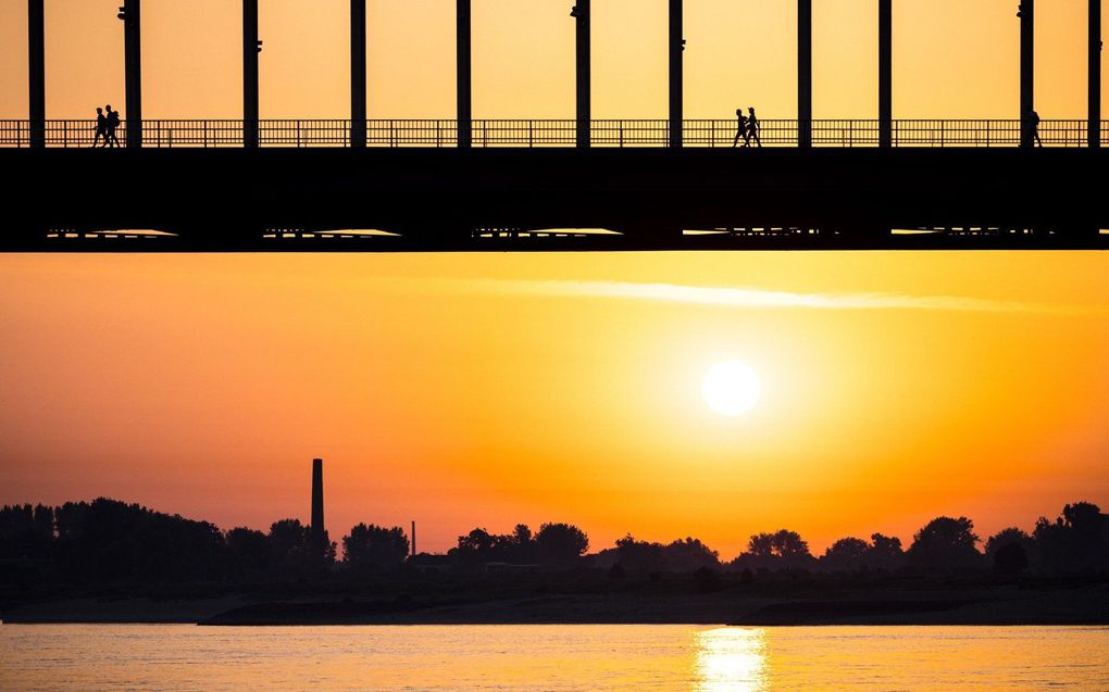 Wandelaars tijdens zonsopgang op De Waalbrug in Nijmegen. beeld ANP, ROB ENGELAAR