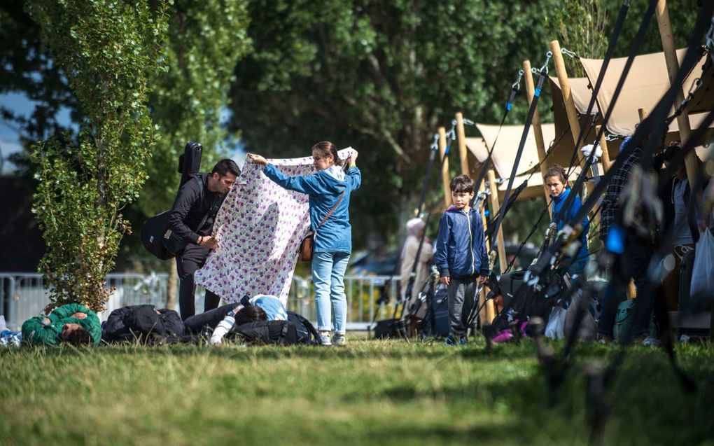 Buiten de poorten van asielcomplex Ter Apel wachten vluchtelingen totdat ze naar binnen kunnen. Sommigen wachten al weken, liggend in het gras. beeld Carel Schutte