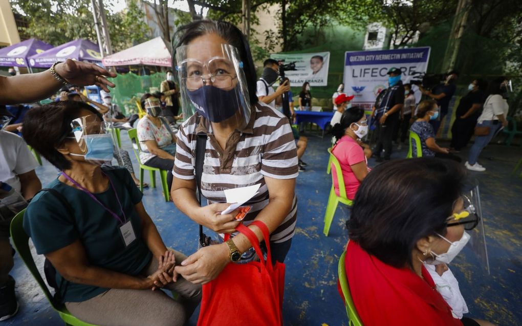 Een Filipijnse vrouw loopt met een doosje ivermectine in de stad Quezon City. Volgens het Nederlands Huisartsen Genootschap is er geen bewijs dat het middel werkt tegen corona. beeld EPA, Rolex Dela Pena