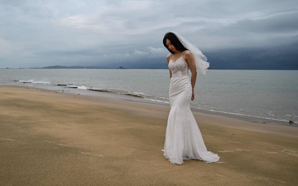 Een bruid poseert op het strand van de Chinese stad Xiamen, met de Taiwanese eilandengroep Kinmen op de achtergrond. Ze laat haar bruiloft niet verbruien door oorlogsdreiging. beeld AFP, Hector Retamal