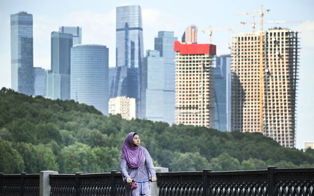 Een vrouw rijdt op een scooter voor de wolkenkrabbers van het International Business Centre van Moskou. beeld AFP, Alexander Nemenov