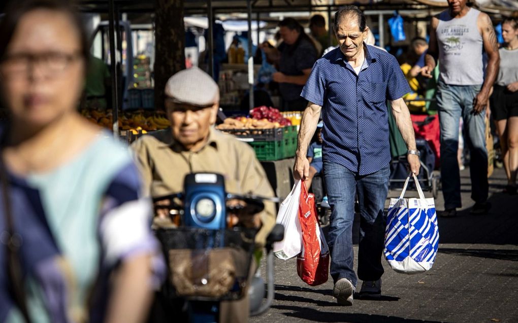 Mensen doen boodschappen op de markt op het Afrikaanderplein in Rotterdam. Boodschappen doen is in een jaar tijd 12 procent duurder geworden. Vooral pasta, brood en zonnebloemolie stegen het sterk in prijs. Beeld ANP, Ramon van Flymen