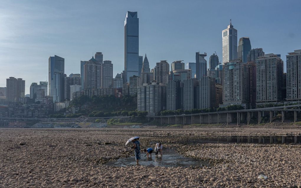 De aanhoudende droogte in China liet de rivier Jialing –een uitloper van de Jangtsekiang– verschrompelen. Op de achtergrond de stad Chongqing waar de temperatuur elf dagen op rij meer dan 40 graden was.  beeld EPA, Stringer