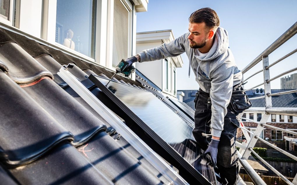 Een installateur plaatst zonnepanelen op het dak van een woning. beeld ANP, Jeffrey Groeneweg