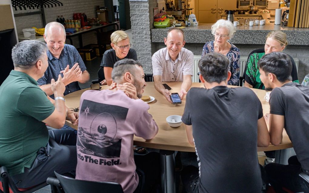 Asielzoekers en vrijwilligers in de hal van de Opstandingskerk in Assen. Ze communiceren onder meer via een vertaal-app met elkaar. beeld Duncan Wijting