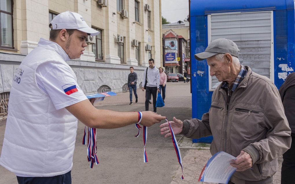 Een vrijwilliger deelt campagnebandjes uit in de kleuren van de Russische nationale vlag tijdens een campagnebijeenkomst voor een referendum over aansluiting bij de Russische Federatie in het centrum van Luhansk, Oekraïne. beeld EPA, Stringer