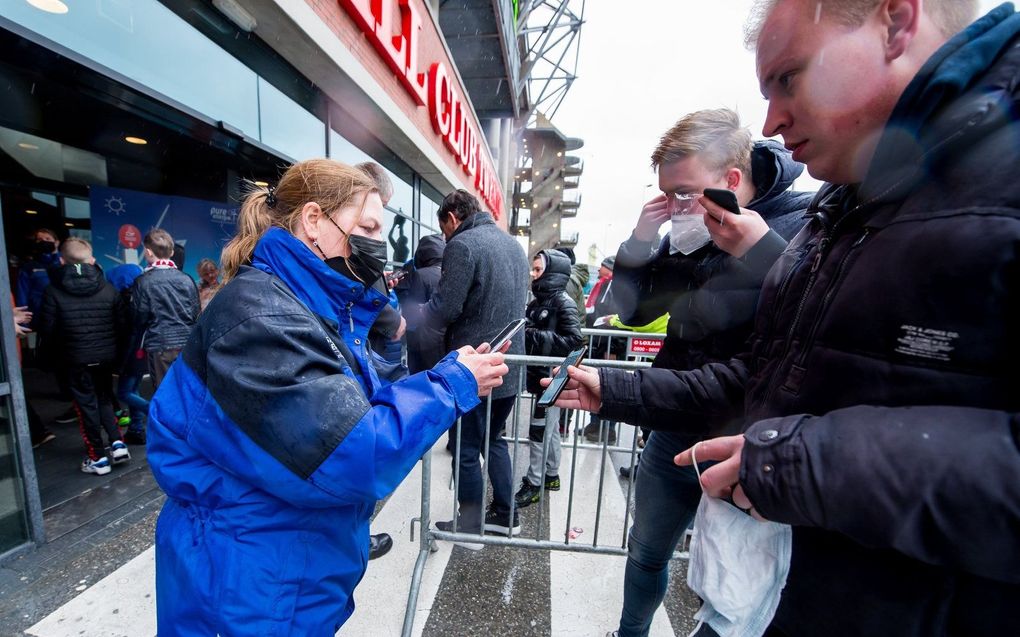 Voordat de bezoekers naar binnen mogen, worden ze gecontroleerd op het coronatoegangsbewijs tijdens een voetbalwedstrijd, februari 2022. beeld ANP, Cor Lasker