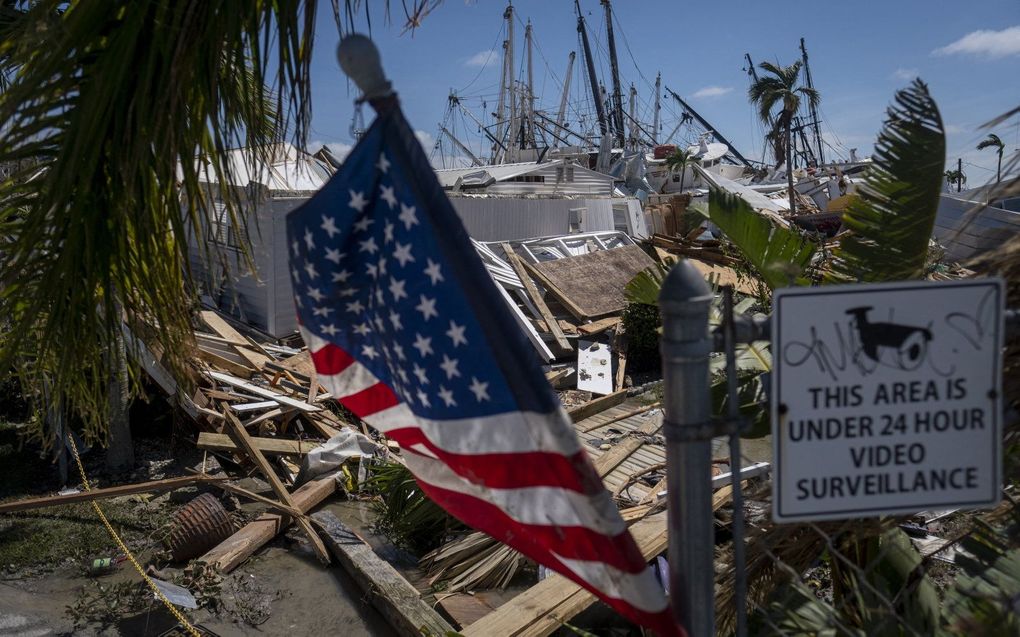 De Amerikaanse vlag wappert bij een stapel aangespoelde boten in de nasleep van orkaan Ian, in Fort Myers, Florida. beeld AFP, Ricardo Arduengo