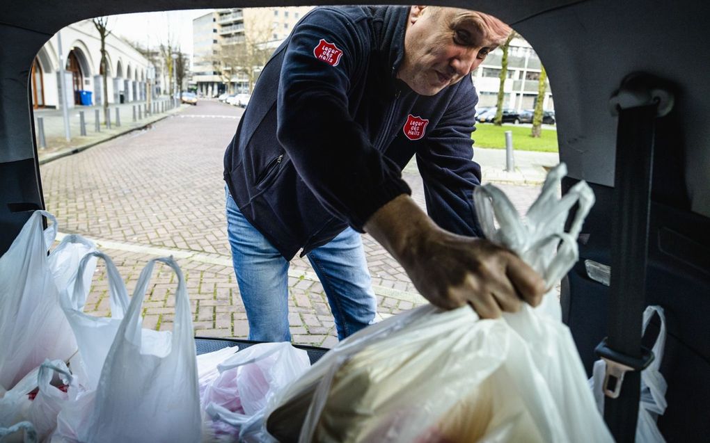 De Rotterdamse D66-fractie hekelt het feit dat het Leger des Heils van sollicitanten vraagt christen te zijn. Foto: een medewerker van het Leger des Heils deelt maaltijdpaketten uit. beeld ANP, Sem van der Wal