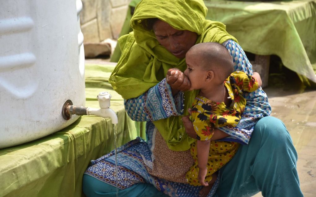 Een vrouw geeft haar kind wat te drinken in een tentenkamp. In het rampgebied is vooral de situatie voor kleine kinderen, zwangere vrouwen en moeders nijpend. beeld EPA, Waqar Hussein