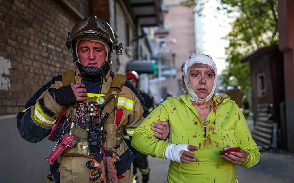 Een Oekraïense brandweerman ontfermt zich in Kiev over een vrouw met een bebloed gezicht, na een golf van luchtaanvallen op vijftien Oekraïense steden. beeld AFP